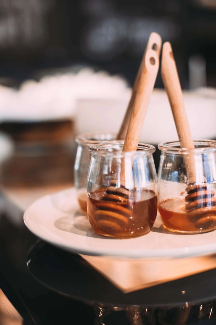 Two clear glass jars of local Illinois honey with wooden dippers
